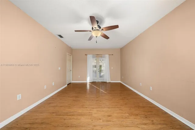 a view of an empty room with window and a ceiling fan