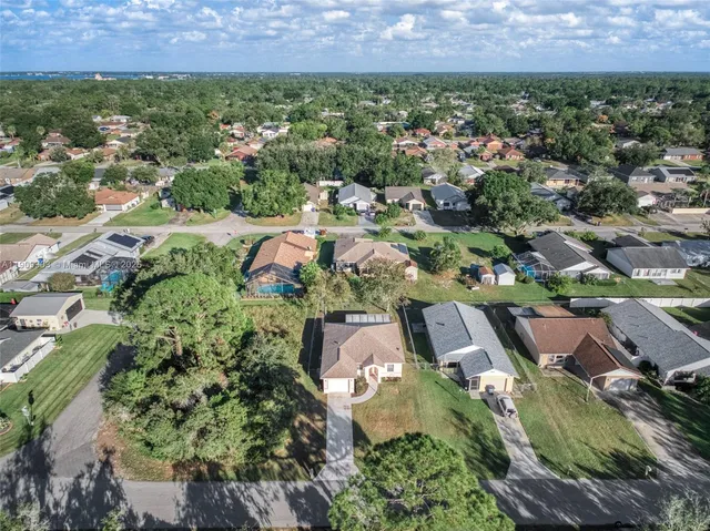 an aerial view of residential houses with outdoor space and trees
