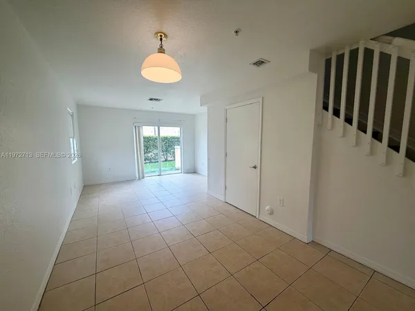 an empty room with chandelier fan and windows