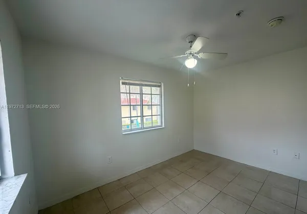 an empty room with ceiling fan and window