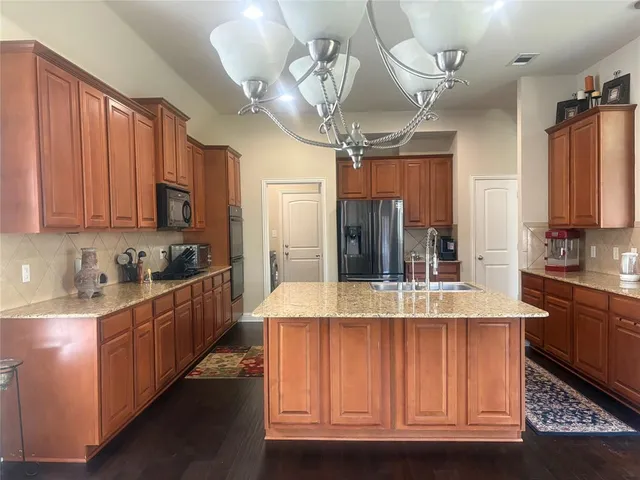 a large kitchen with kitchen island granite countertop a sink stainless steel appliances and cabinets