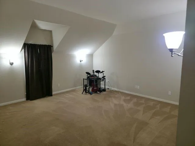 an empty room with a chandelier fan and a window