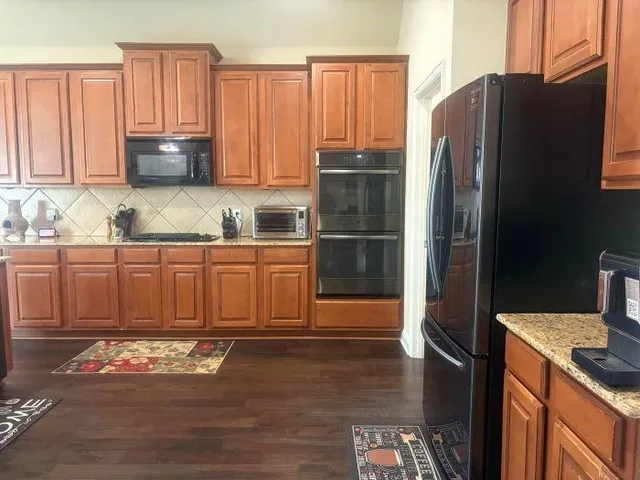 a kitchen with granite countertop a refrigerator stove and microwave