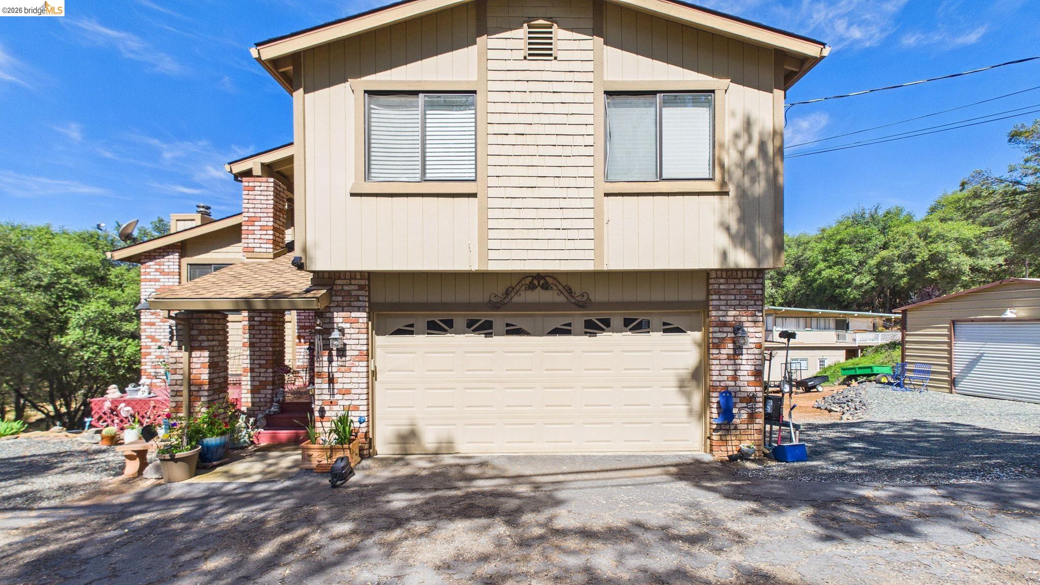 Two-story residence featuring a two-car garage, brick facade detailing, and a covered entry porch