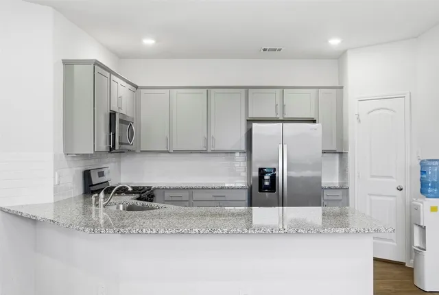 a kitchen with stainless steel appliances granite countertop a refrigerator and a sink