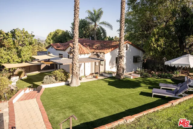 a view of a patio with table and chairs potted plants and large tree