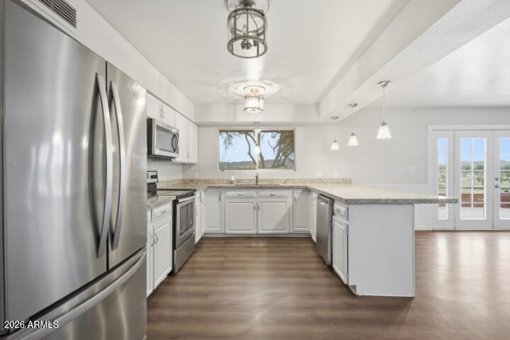 19402 West Lynx Road Buckeye, AZ 85326 - Photo 8 of 42 a large kitchen with a refrigerator a sink dishwasher a stove and white cabinets with wooden floor