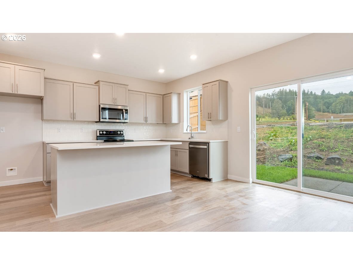 9194 Southeast Azalea Street Happy Valley, OR 97086 - Photo 10 of 32 a kitchen with kitchen island a sink stainless steel appliances and cabinets