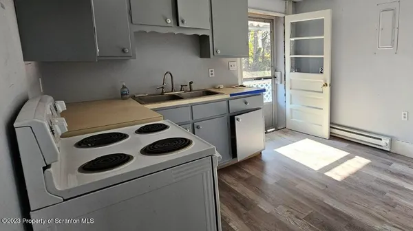 a kitchen with a white stove top oven and white countertops with wooden floor