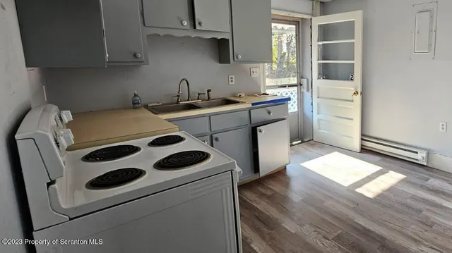 a kitchen with a white stove top oven and white countertops with wooden floor