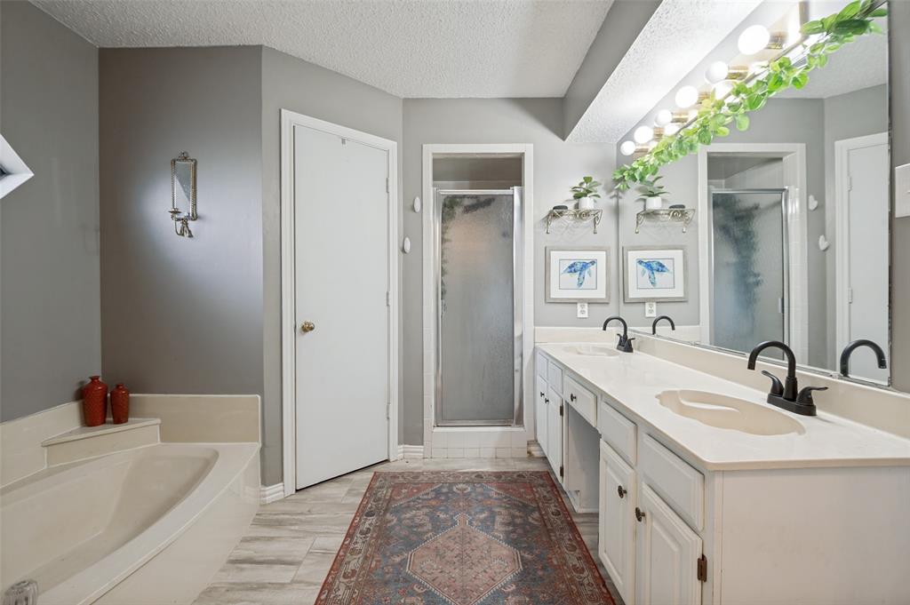 1006 Ridgeview Carrollton, TX 75007 - Photo 16 of 27 Built-in bathtub, double vanity countertop, matte black faucets, and separate shower enclosure