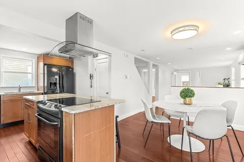 a kitchen with stainless steel appliances kitchen island granite countertop a table chairs in it and wooden floors