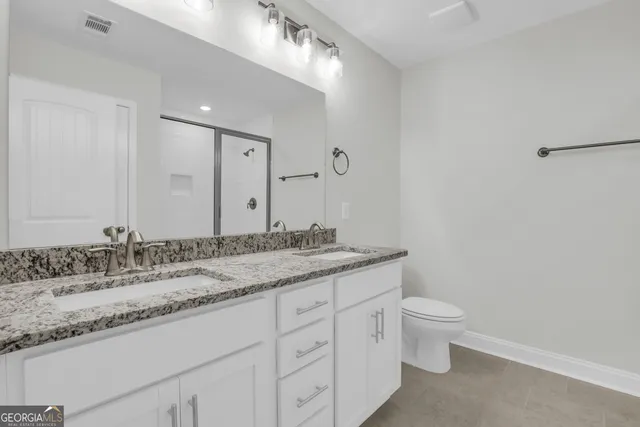 a bathroom with a granite countertop sink a toilet and a mirror