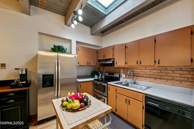 a kitchen with stainless steel appliances kitchen island granite countertop a refrigerator a stove top oven a sink and dishwasher