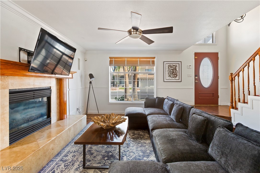2829 Via Florentine Street Henderson, NV 89074 - Photo 30 of 48 Living room with stairway, a tile fireplace, ornamental molding, a ceiling fan, and wood finished floors