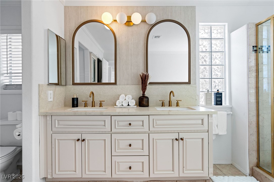 2829 Via Florentine Street Henderson, NV 89074 - Photo 37 of 48 Full bathroom featuring double vanity, a shower stall, decorative backsplash, crown molding, and light tile patterned floors
