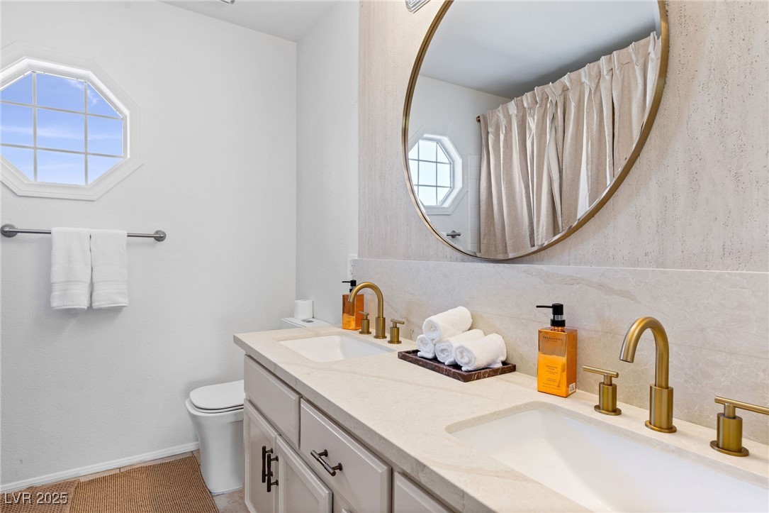 2829 Via Florentine Street Henderson, NV 89074 - Photo 45 of 48 Bathroom featuring double vanity, a shower with shower curtain, and tasteful backsplash