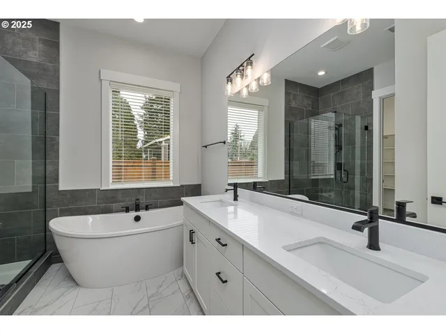 a bathroom with a double vanity sink large mirror and a bathtub