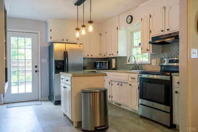 a kitchen with stainless steel appliances granite countertop a refrigerator a sink a stove and white cabinets