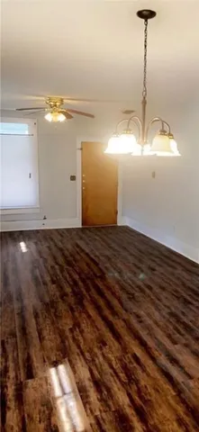 a view of an empty room with window and chandelier fan