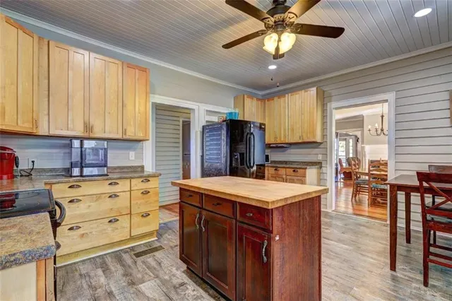 a kitchen with stainless steel appliances kitchen island granite countertop a stove top oven a sink dishwasher a dining table and chairs with wooden floor