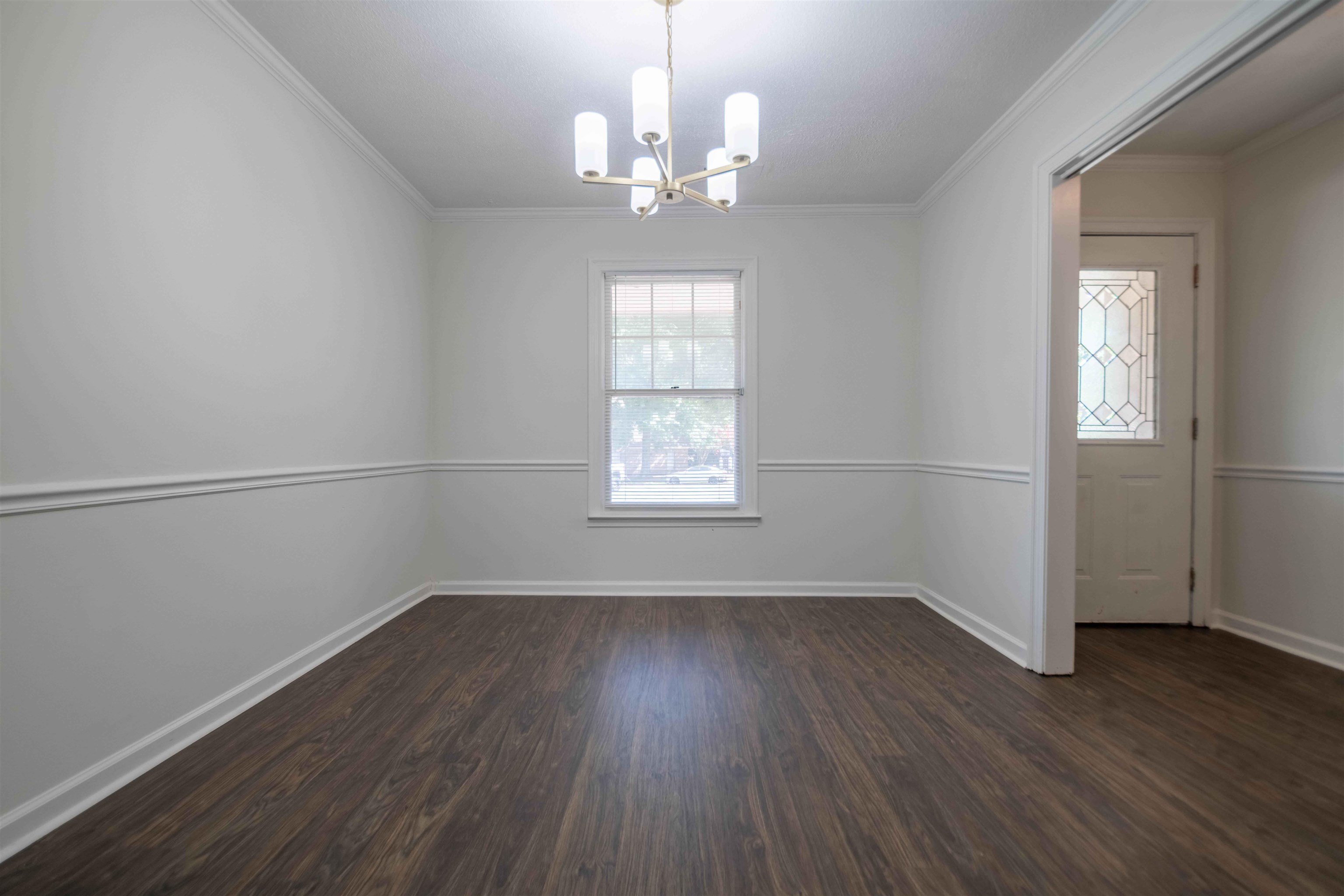 7800 Buck Ridge Cove Memphis, TN 38016 - Photo 8 of 36 Spacious room featuring dark wood-finish flooring, white walls with chair rail molding, and crown molding