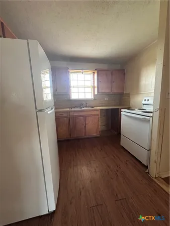 a kitchen with sink refrigerator and wooden floor