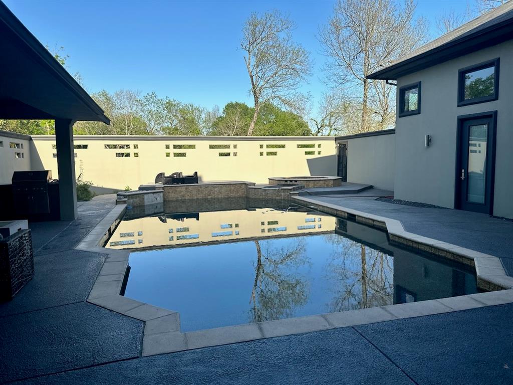 Courtyard with pool house & pool with grilling area, a patio, and an outdoor kitchen
