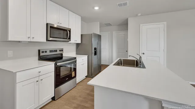 a kitchen with white cabinets and stainless steel appliances
