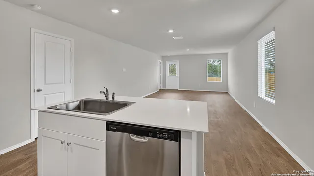 a kitchen with granite countertop white cabinets stainless steel appliances and wooden floor