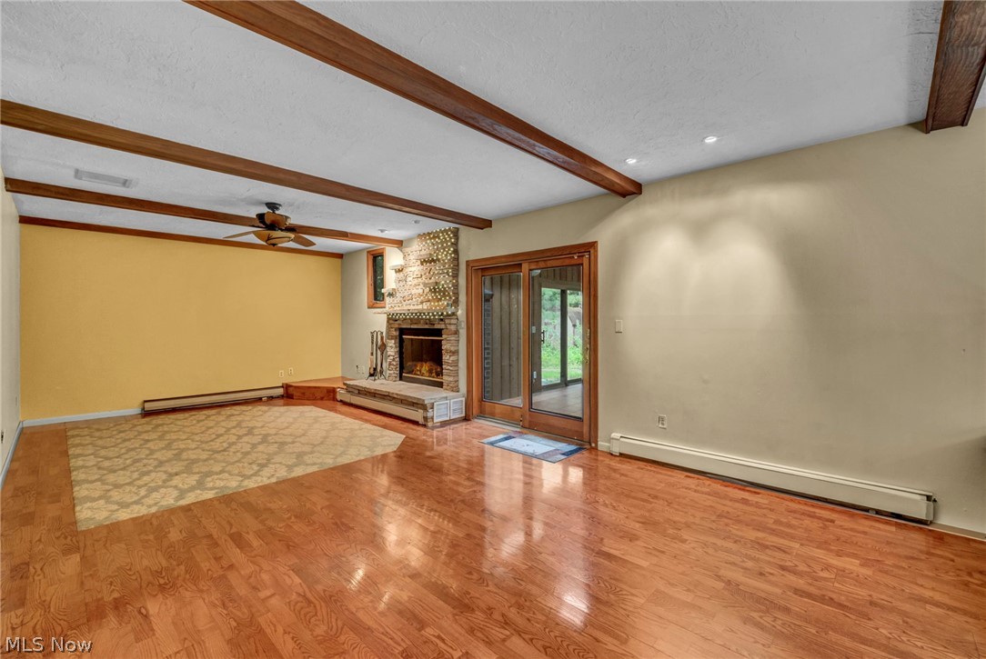 6845 Liberty Road Solon, OH 44139 - Photo 16 of 47 Spacious room featuring wood-finish flooring, exposed ceiling beams, and a stone-faced fireplace
