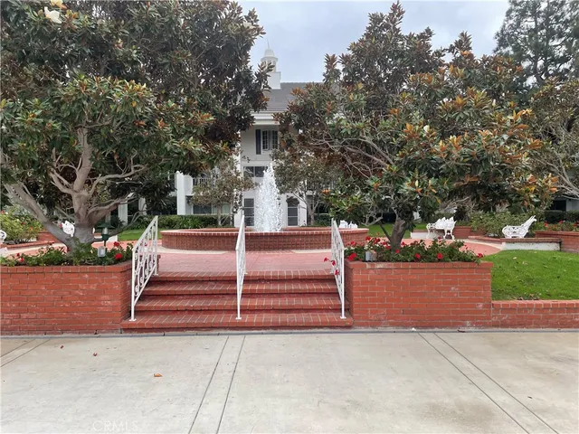 a park view with a bench plants and large trees