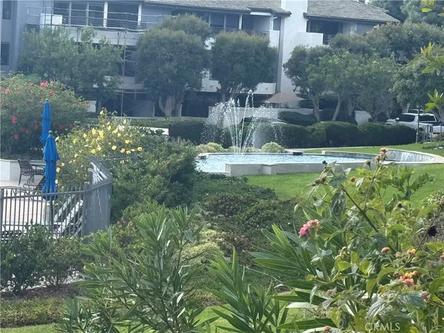 a backyard of a house with fountain table and chairs with plants
