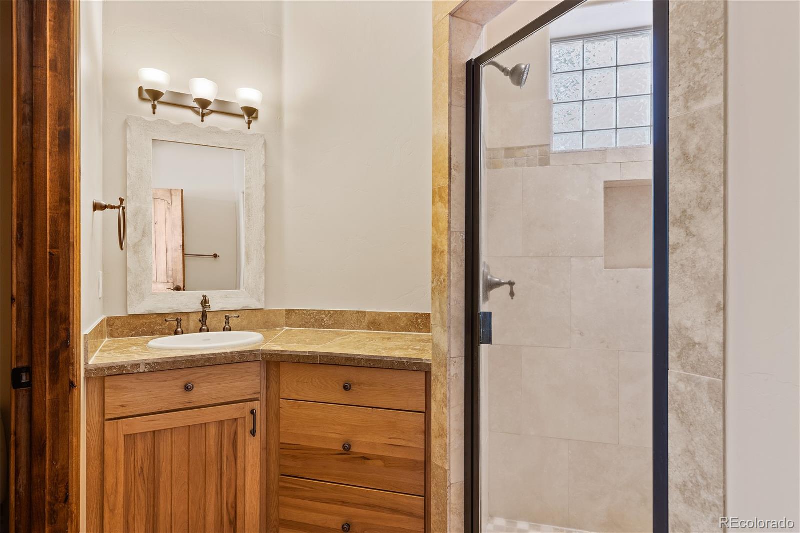 2505 Big Bear Circle Sedalia, CO 80135 - Photo 38 of 50 a bathroom with a granite countertop sink a mirror and a shower
