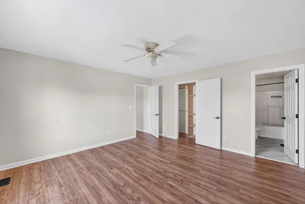 an empty room with wooden floor and ceiling fan
