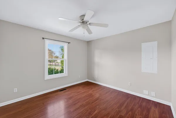 an empty room with wooden floor fan and windows