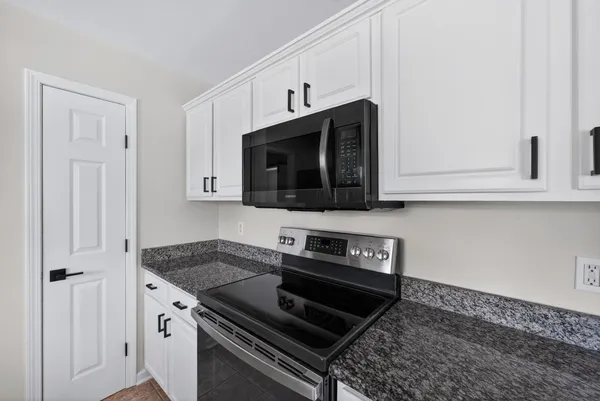 a kitchen with stainless steel appliances granite countertop white cabinets and black stove top oven with granite countertops