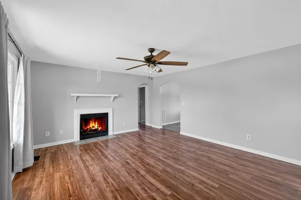 a view of empty room with wooden floor fireplace and a window