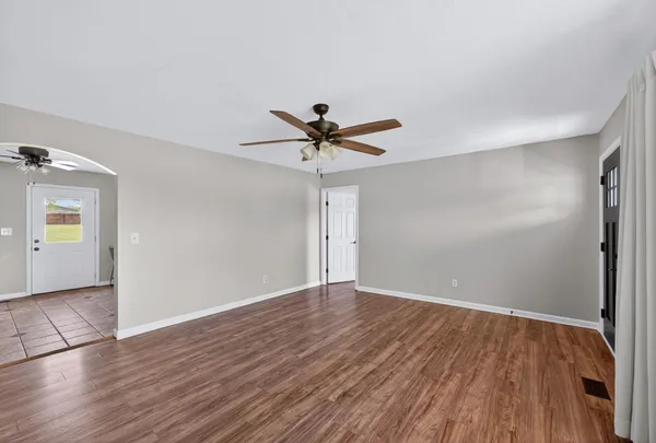 an empty room with wooden floor and ceiling fan