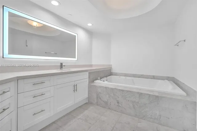 a spacious bathroom with a granite countertop sink mirror and bathtub