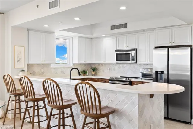 a kitchen with stainless steel appliances granite countertop a table chairs microwave and sink