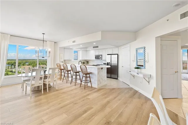 a large white kitchen with lots of white furniture a dining table and chairs