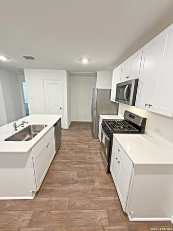 a large white kitchen with stainless steel appliances granite countertop a stove and a sink