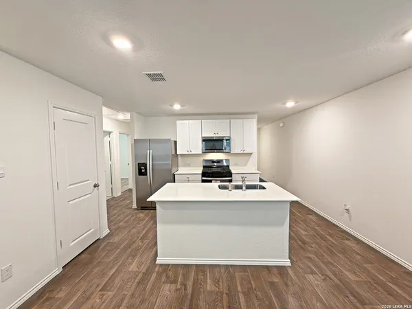a large white kitchen with wooden floor