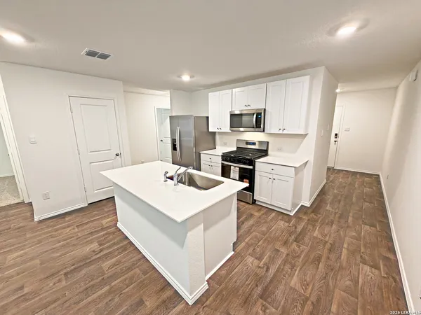 a kitchen that has a lot of white cabinets and wooden floor