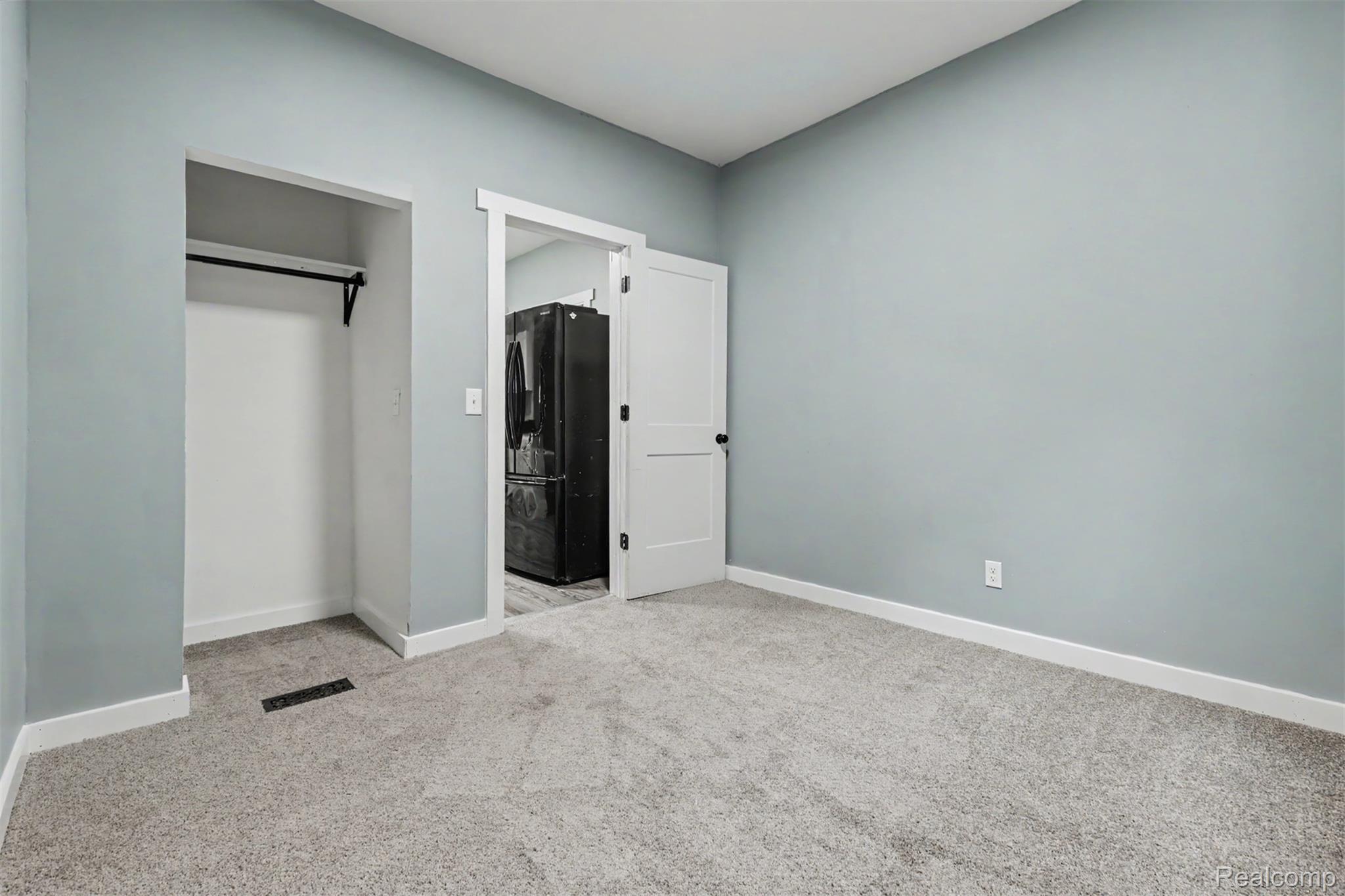 8397 Lane Street Detroit, MI 48209 - Photo 18 of 41 Room featuring light blue walls, gray carpet, white trim, and a built-in closet with a hanging rod