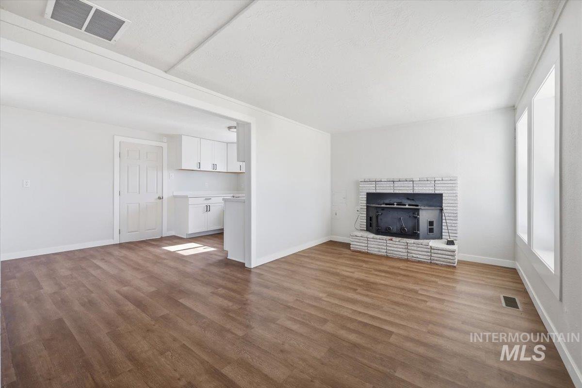 956 Southeast Hamilton Road Mountain Home, ID 83647 - Photo 12 of 34 Spacious interior with wood-finish flooring, a white brick fireplace, and multiple windows