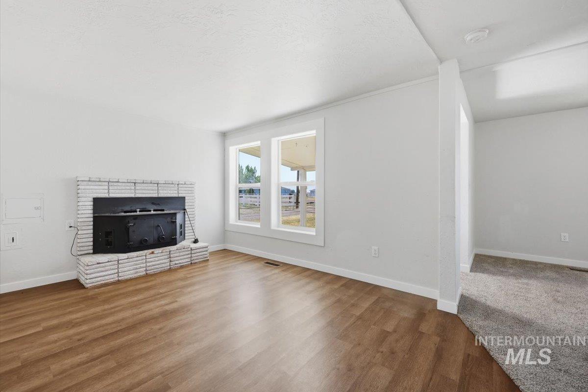 956 Southeast Hamilton Road Mountain Home, ID 83647 - Photo 13 of 34 Living area featuring wood-finish flooring, a white brick fireplace, and dual windows