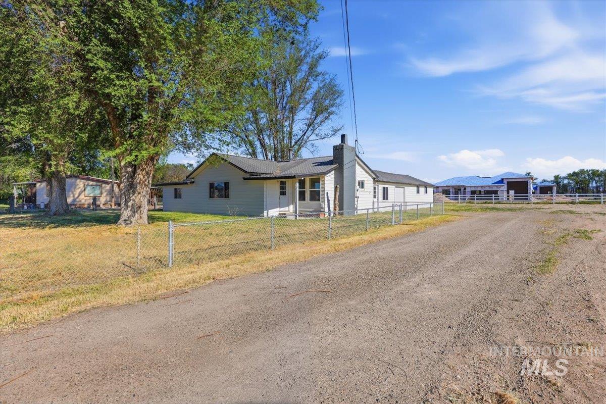 956 Southeast Hamilton Road Mountain Home, ID 83647 - Photo 2 of 34 Single-story residence featuring light-colored siding, a dark shingle roof, and a prominent exterior chimney