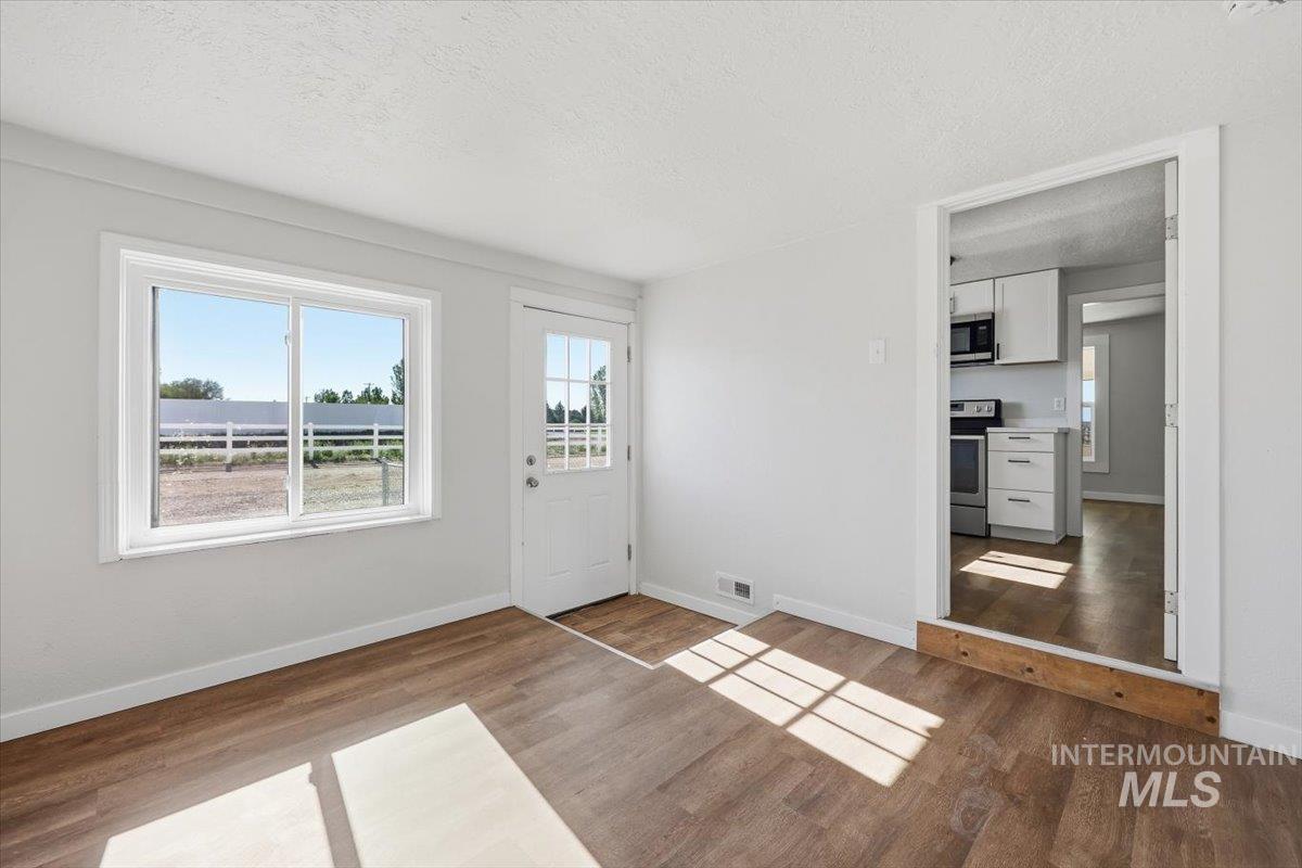 956 Southeast Hamilton Road Mountain Home, ID 83647 - Photo 24 of 34 Light-filled interior space featuring wood-finish flooring, a white paneled door with glass inserts, and a large window providing expansive outdoor views